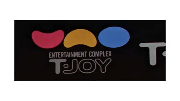 劇場スクリーンに投影されたT・ジョイ博多のロゴ画像。一番左のピンク色の図形だけ輪郭がぼやけて見える。