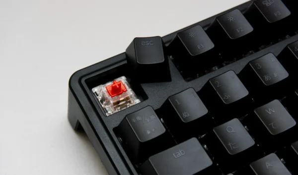 Escape キーだけ外した状態の写真。赤色の軸が見えている。外されたキーキャップが横に置かれている。